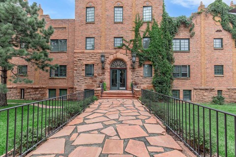 A red brick building with a black iron fence and a stone pathway leading to the entrance.