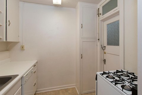 A small kitchen with a white stove and cabinets.