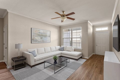 A living room with a white couch, a painting on the wall, and a ceiling fan.
