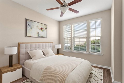 A bedroom with a large bed, a ceiling fan, and a painting on the wall.