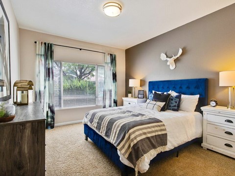 A bedroom with a blue headboard and a striped blanket on the bed.