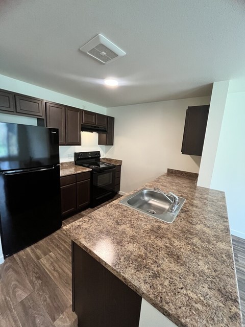 A kitchen with a granite countertop and a black refrigerator.
