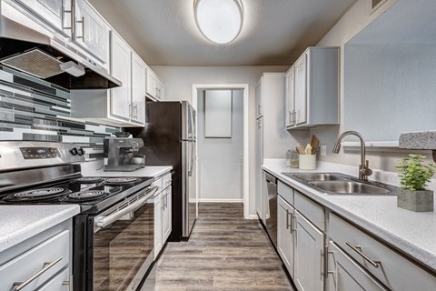 A modern kitchen with a black stove top oven and white cabinets.
