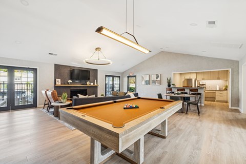 A pool table is in the middle of a spacious room with a fireplace and a television.