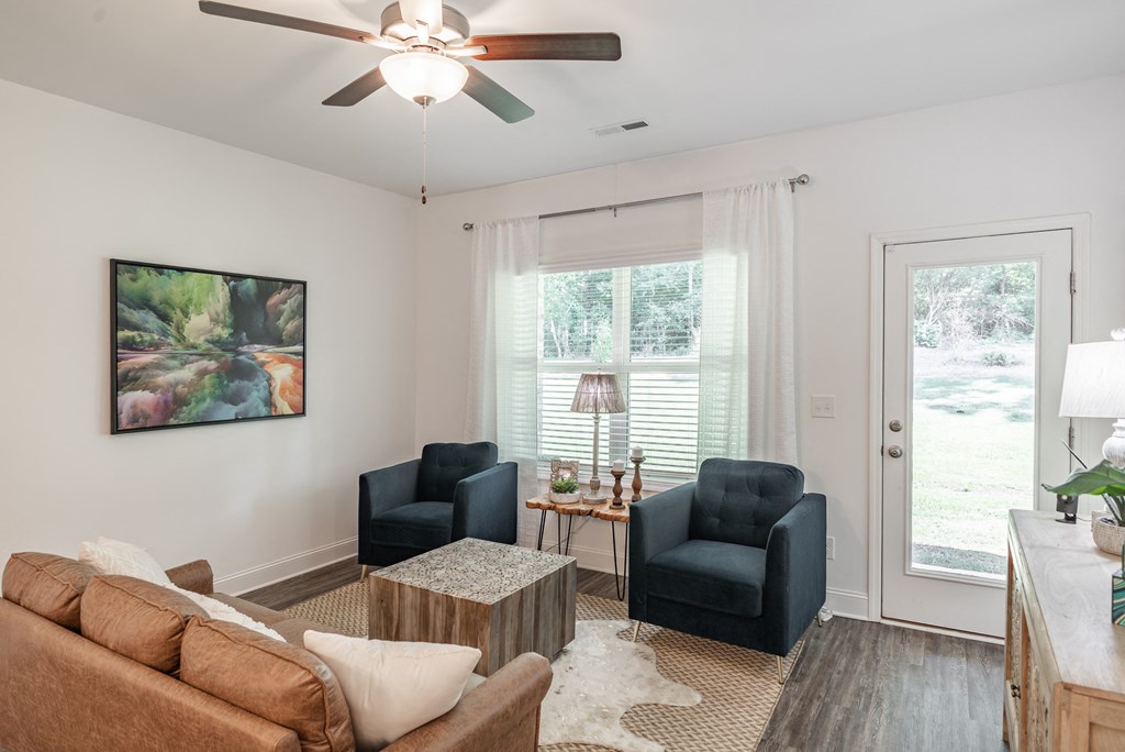 a living room with a ceiling fan and two chairs