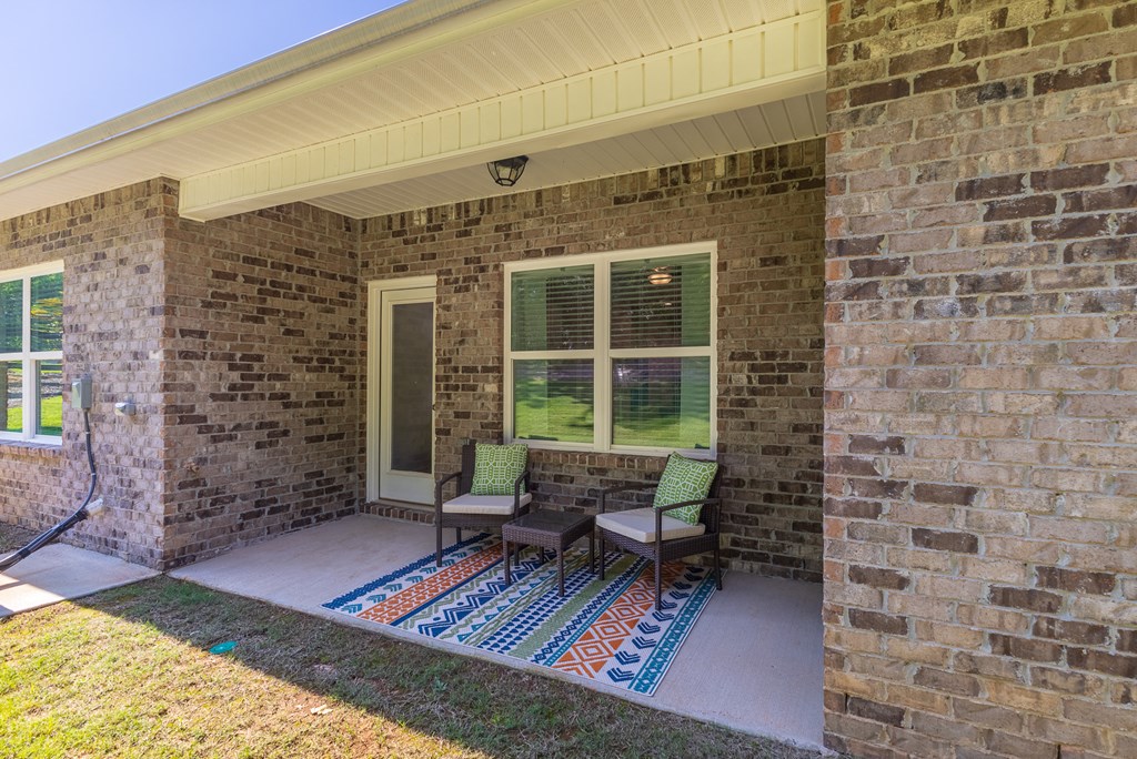a patio with two chairs and a rug in front of a brick building