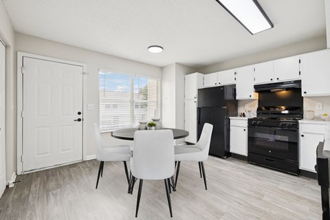 A kitchen with a table and chairs in front of a white door.