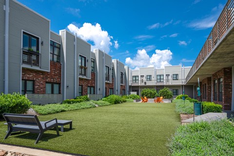A sunny day at a modern residential area with a grassy lawn and benches.