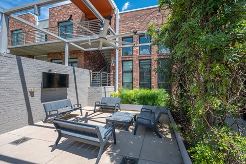 A patio with a table and chairs is in front of a brick building.