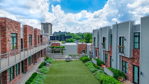 A courtyard surrounded by buildings with a blue sky and clouds in the background.