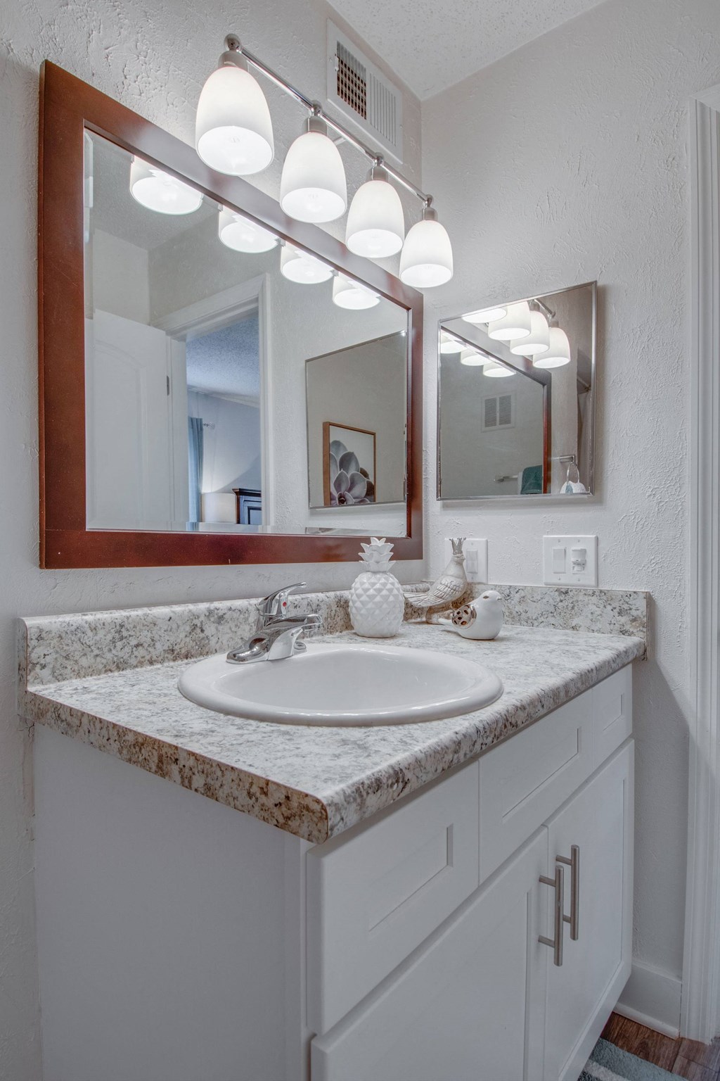 Master bathroom with floating vanities, quartz countertops, backlit vanity mirror, walk in shower with Euro shower door and quartz topped bench seat at Nob Hill Apartments, Nashville