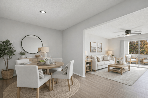 A well-lit, modern dining room with a round mirror and a wooden table.
