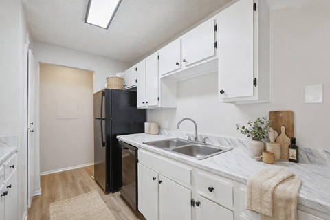 A kitchen with white cabinets and a black fridge.