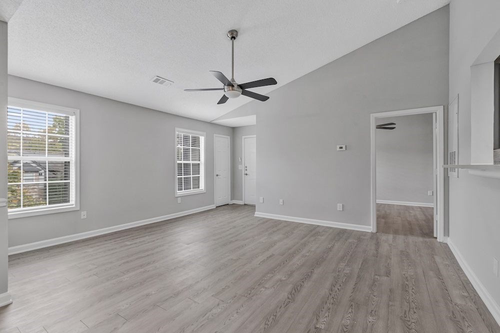 A room with a ceiling fan and wooden flooring.