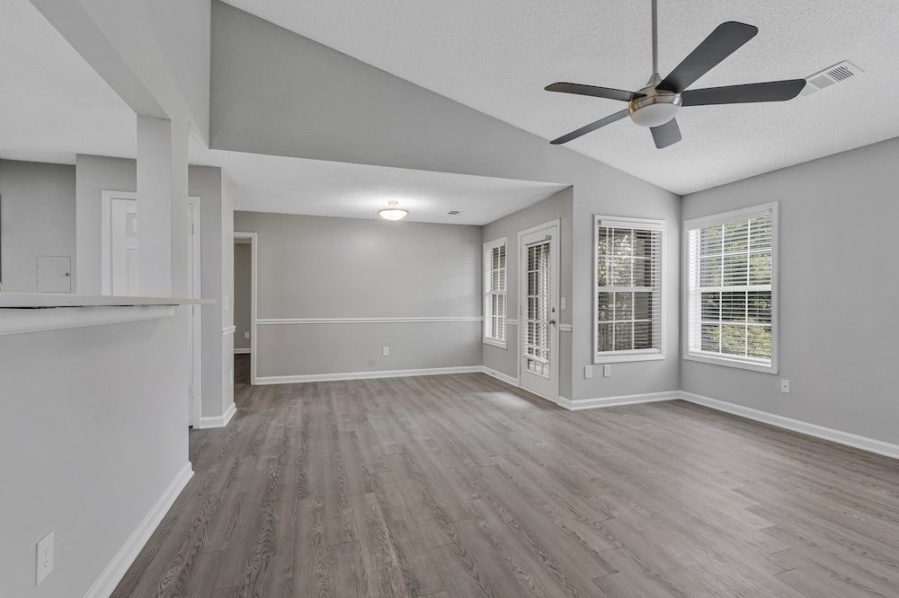 A spacious room with a ceiling fan and hardwood flooring.