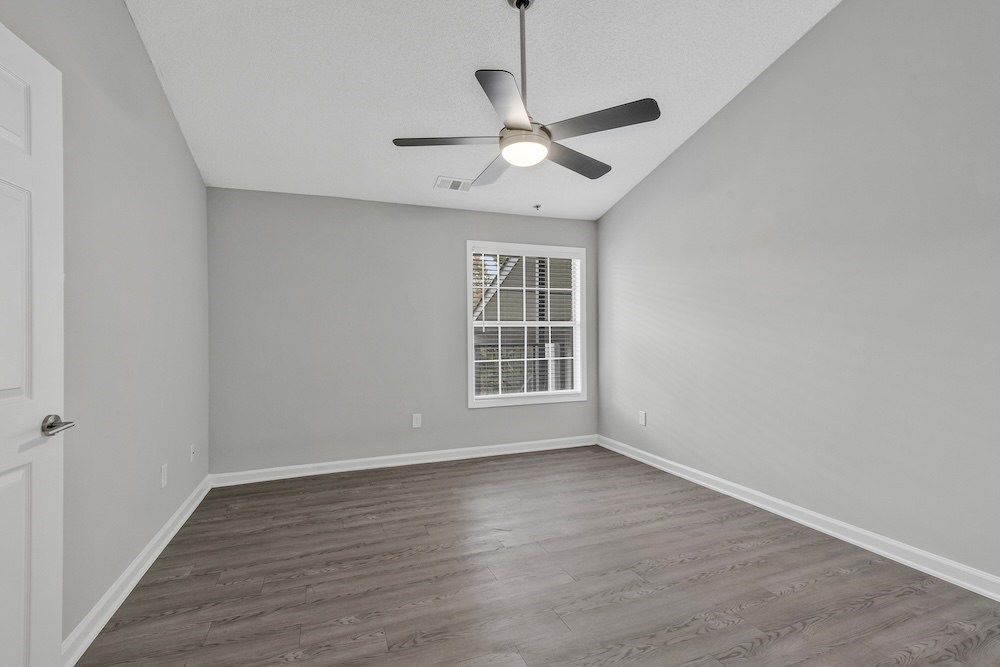 A room with a ceiling fan and a window with blinds.