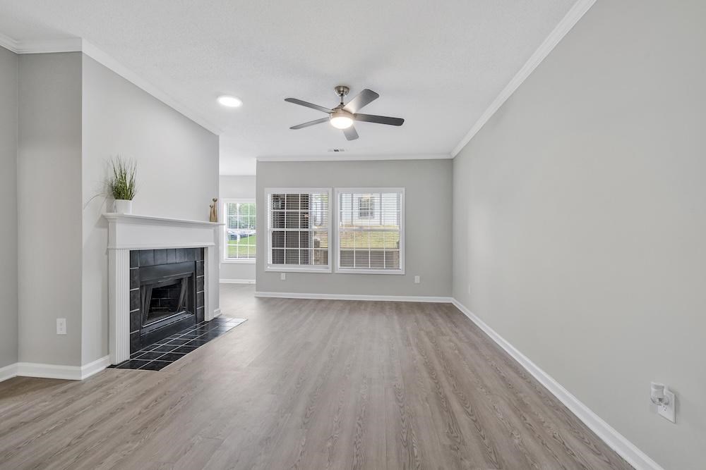 A spacious living room with a fireplace and a ceiling fan.