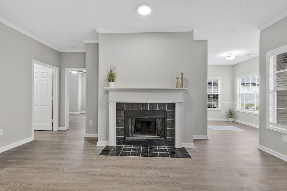 A spacious living room with a fireplace and a rug.