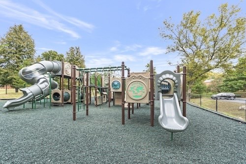 A playground with a green slide and a grey slide.