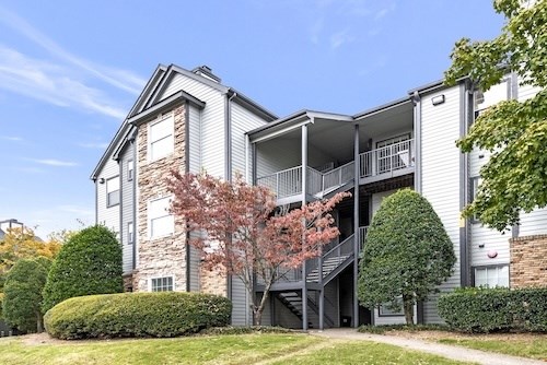 A modern two-story apartment building with a balcony on the second floor.