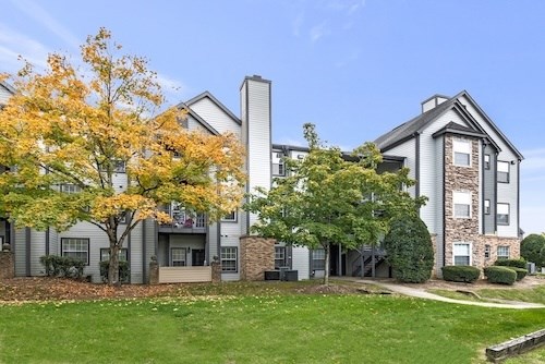 A large apartment complex with a tree with yellow leaves in front.
