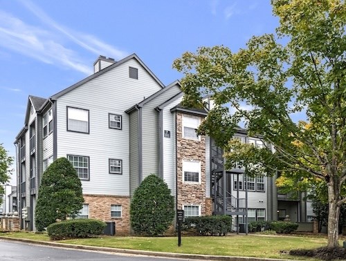A modern apartment building with a mix of grey and stone facades.