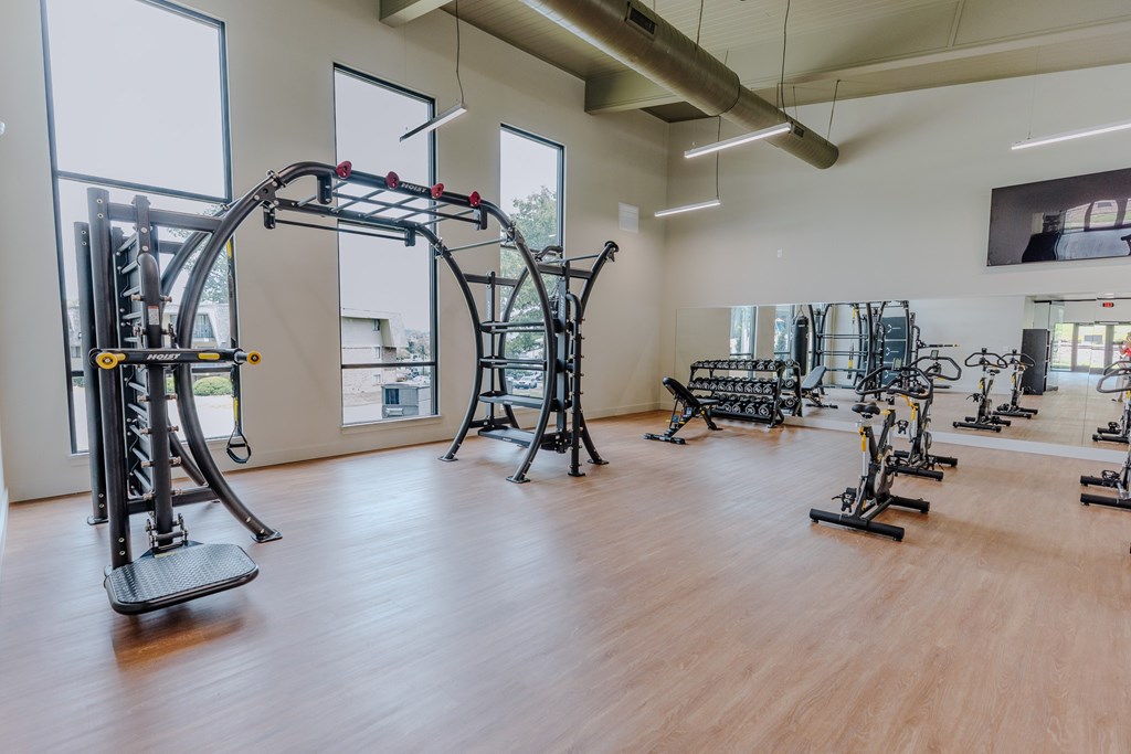 A gym with a variety of equipment including a squat rack, bench press, and leg press machines.
