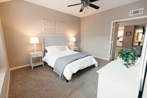 A bedroom with a large bed and a ceiling fan.
