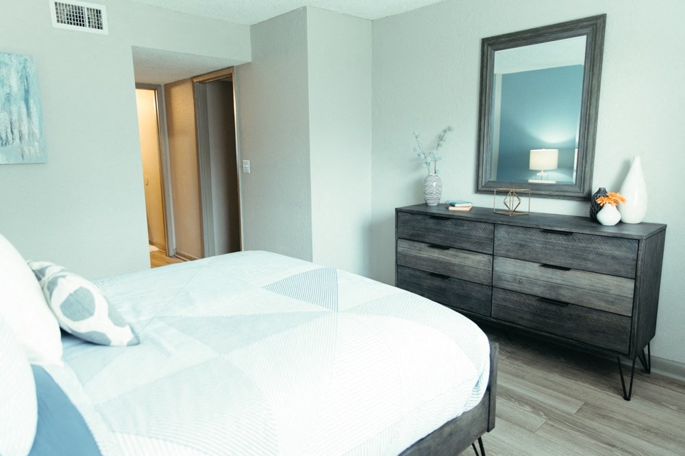 a bedroom with a bed and a dresser with a mirror
