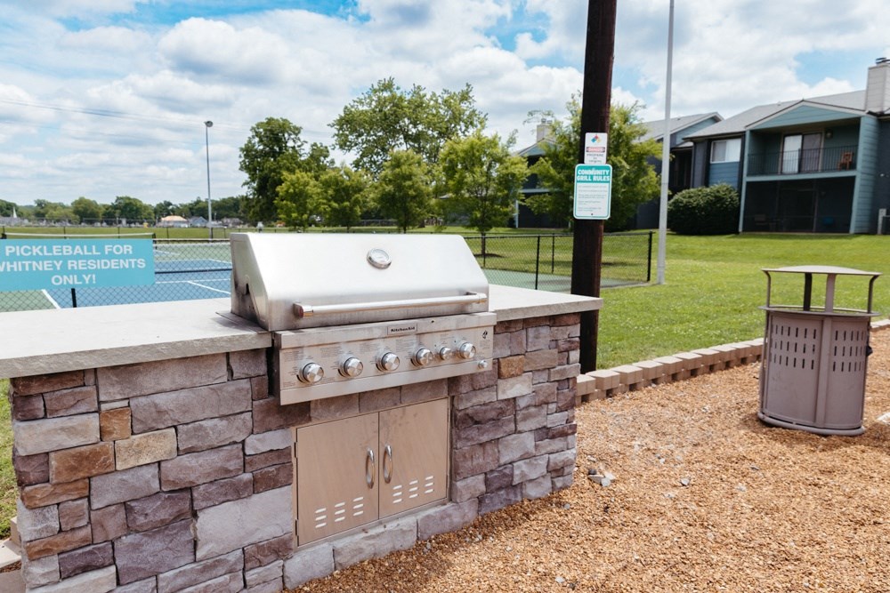 a barbecue grill in the backyard of a house with a tennis court