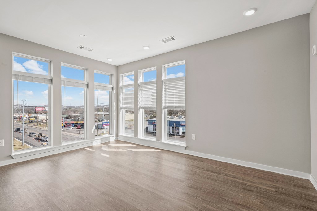 a living room with hardwood floors and large windows