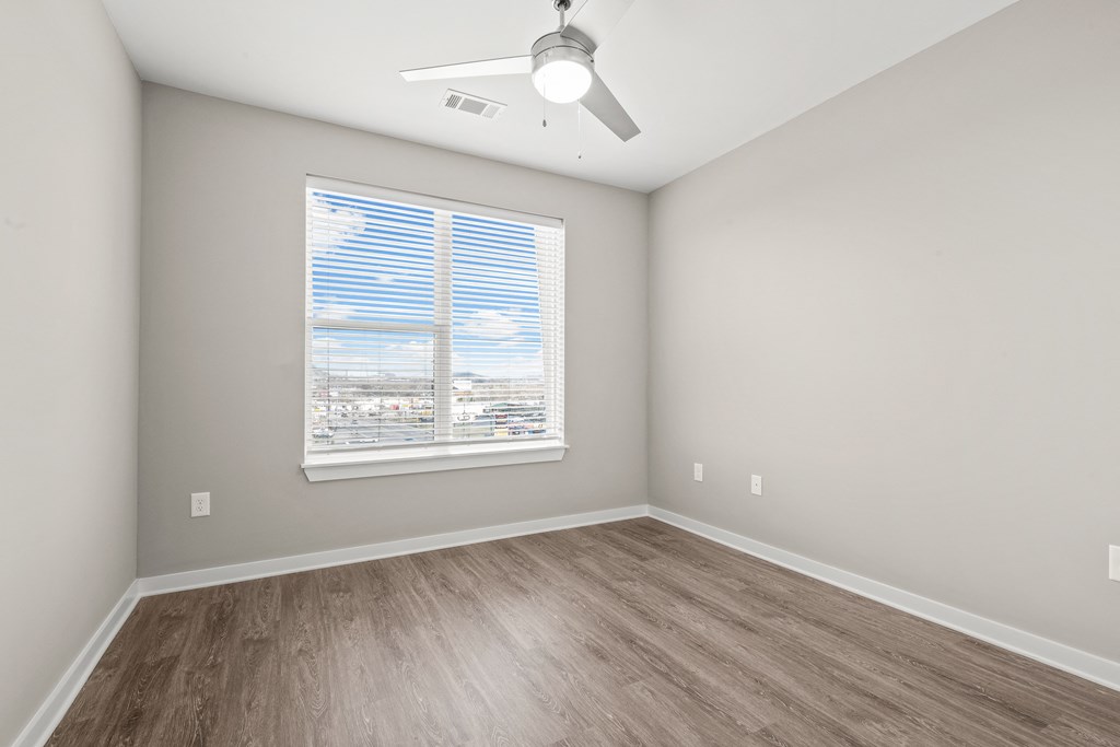 an empty bedroom with a large window and a ceiling fan