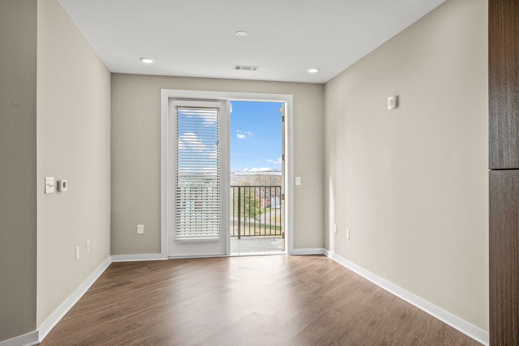 a bedroom with hardwood floors and a doorway leading to a balcony
