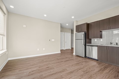 a kitchen and living room with wood flooring and a stainless steel refrigerator