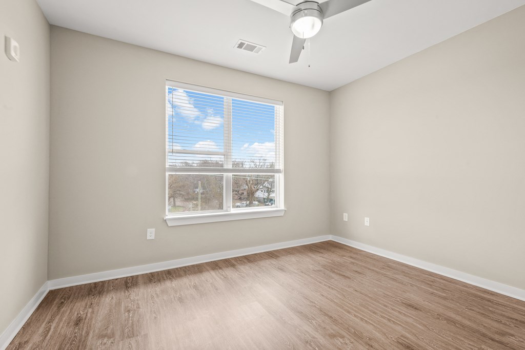 a bedroom with a large window and hardwood floors