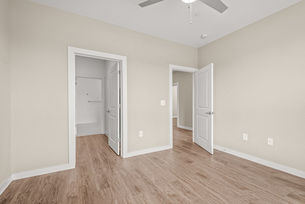 a bedroom with hardwood floors and beige walls