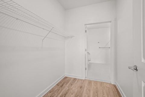 a bedroom with white walls and wood flooring and a closet