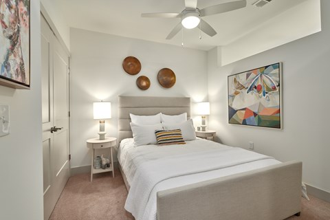 A bedroom with a large bed and a ceiling fan.