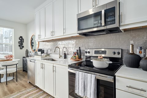 A modern kitchen with a stove top oven and a microwave above it.
