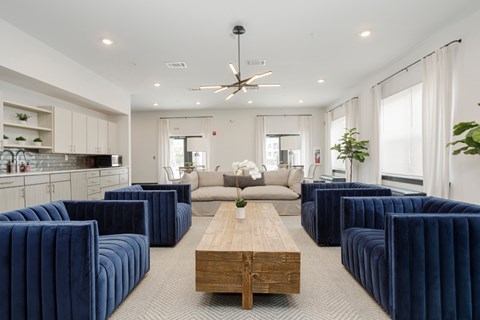 A modern living room with a long wooden table and blue velvet chairs.