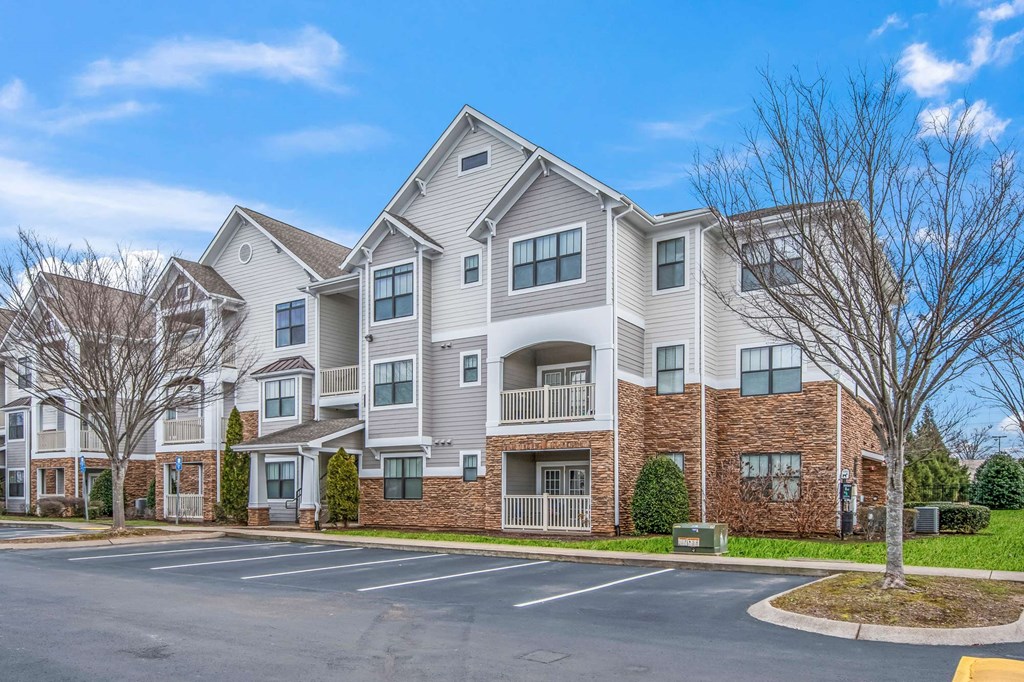 a street view of an apartment building with a parking lot
