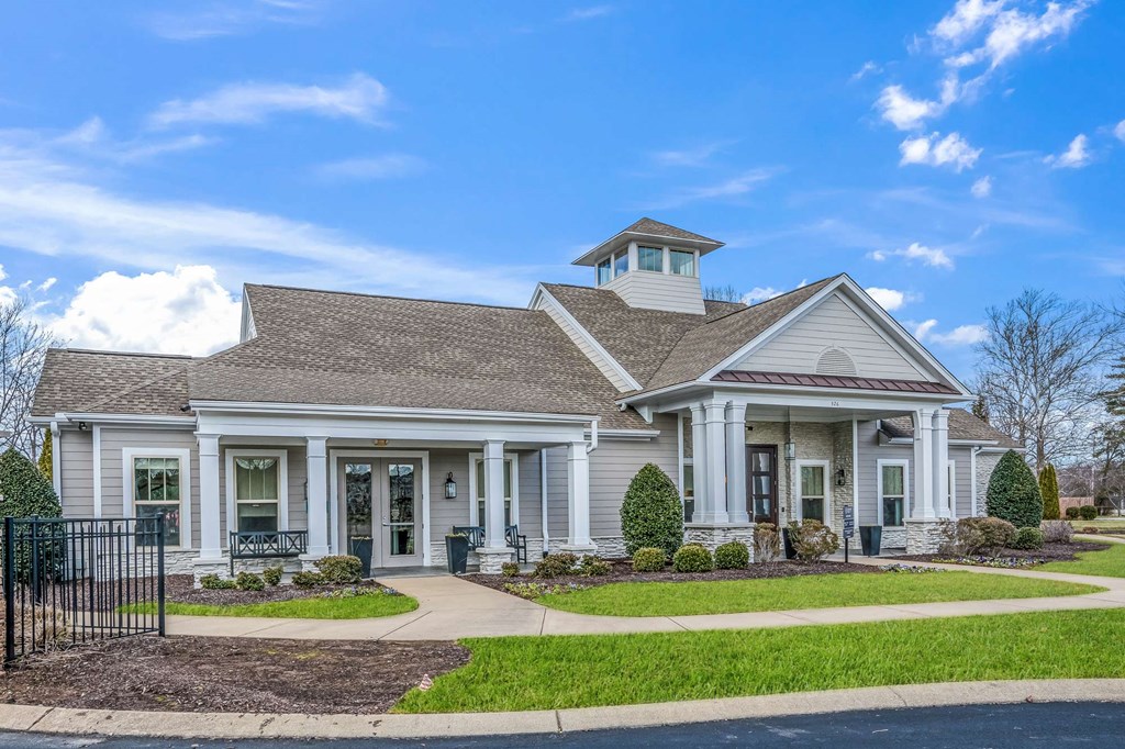 the front of a white house with a walkway and grass