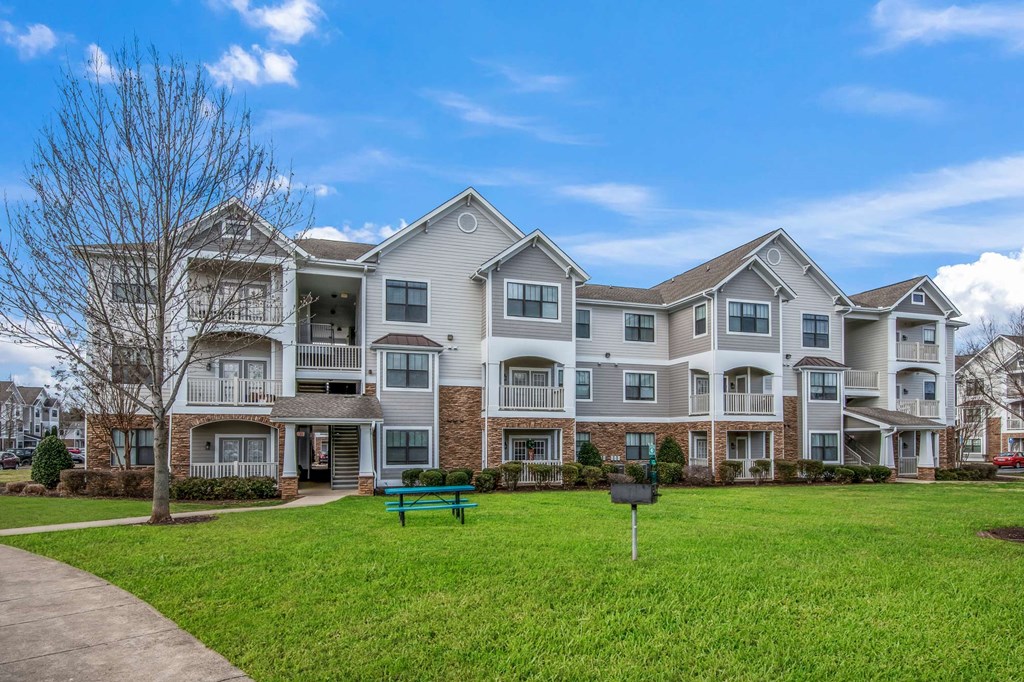 an apartment building with a green bench in front of it