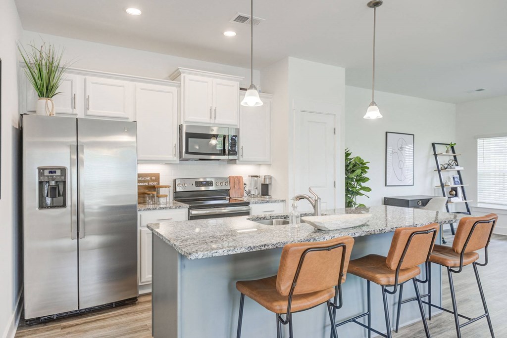 a kitchen with white cabinets and a large island with a granite countertop