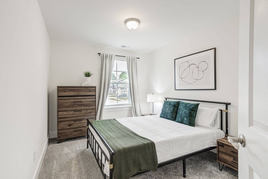 a bedroom with a medium sized bed and a dresser with a window