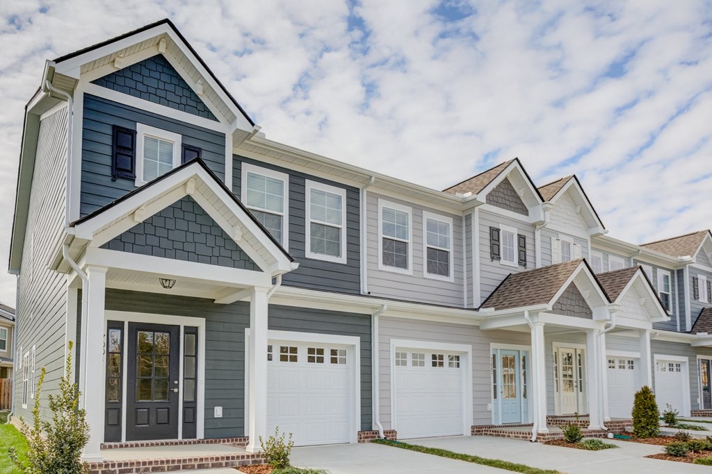 a large house with gray siding and white doors