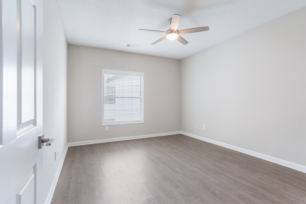 A room with a ceiling fan and a window with blinds.