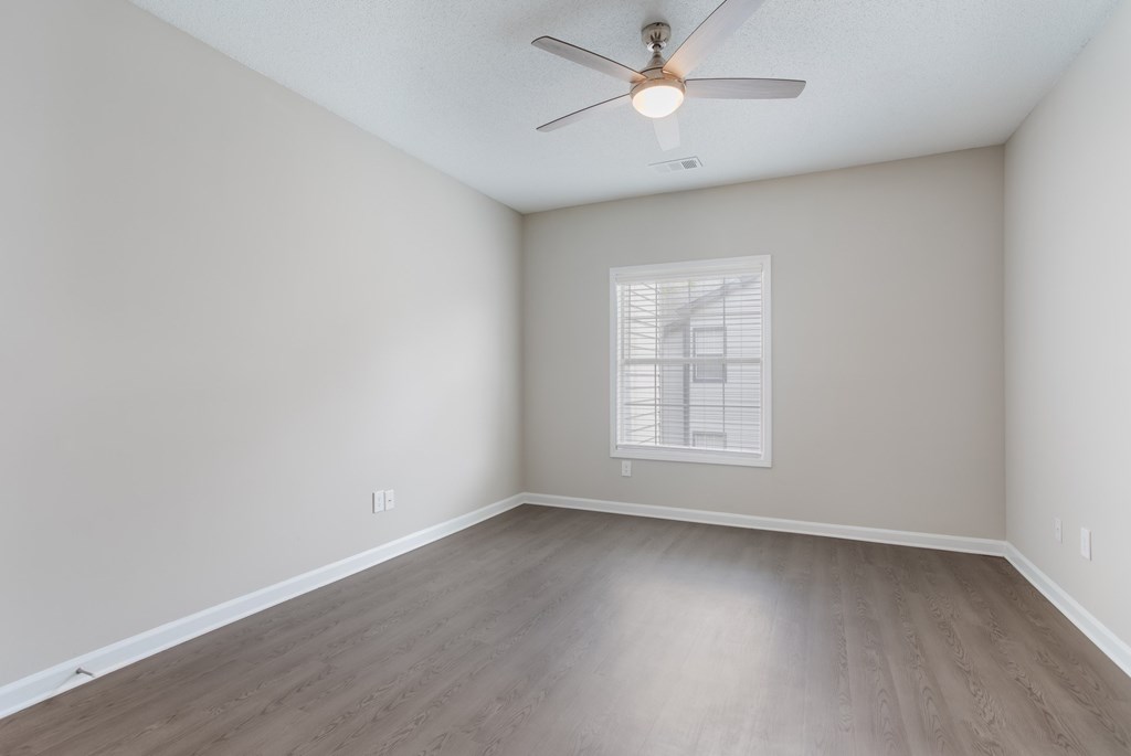 A room with a ceiling fan and a window with blinds.