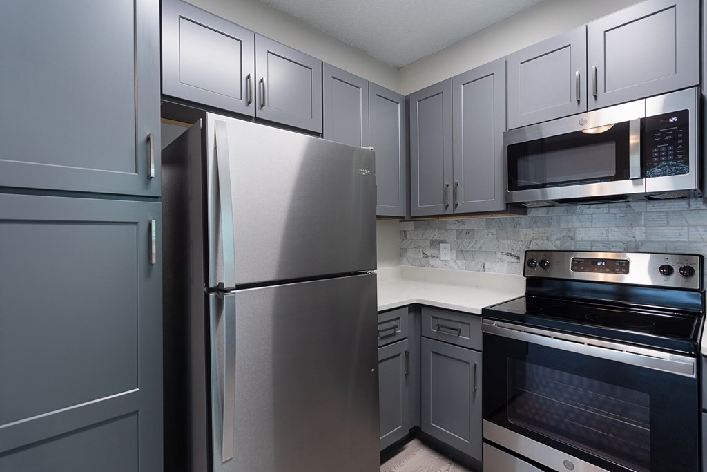 A kitchen with a refrigerator, oven, and microwave.