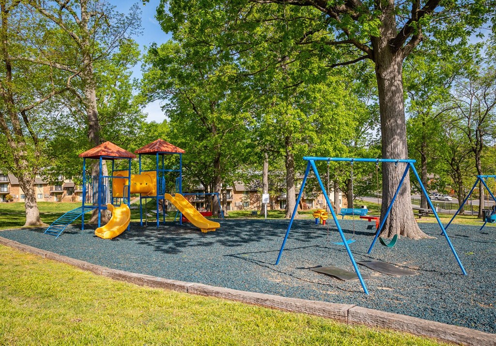 A playground with a yellow slide and blue swings.